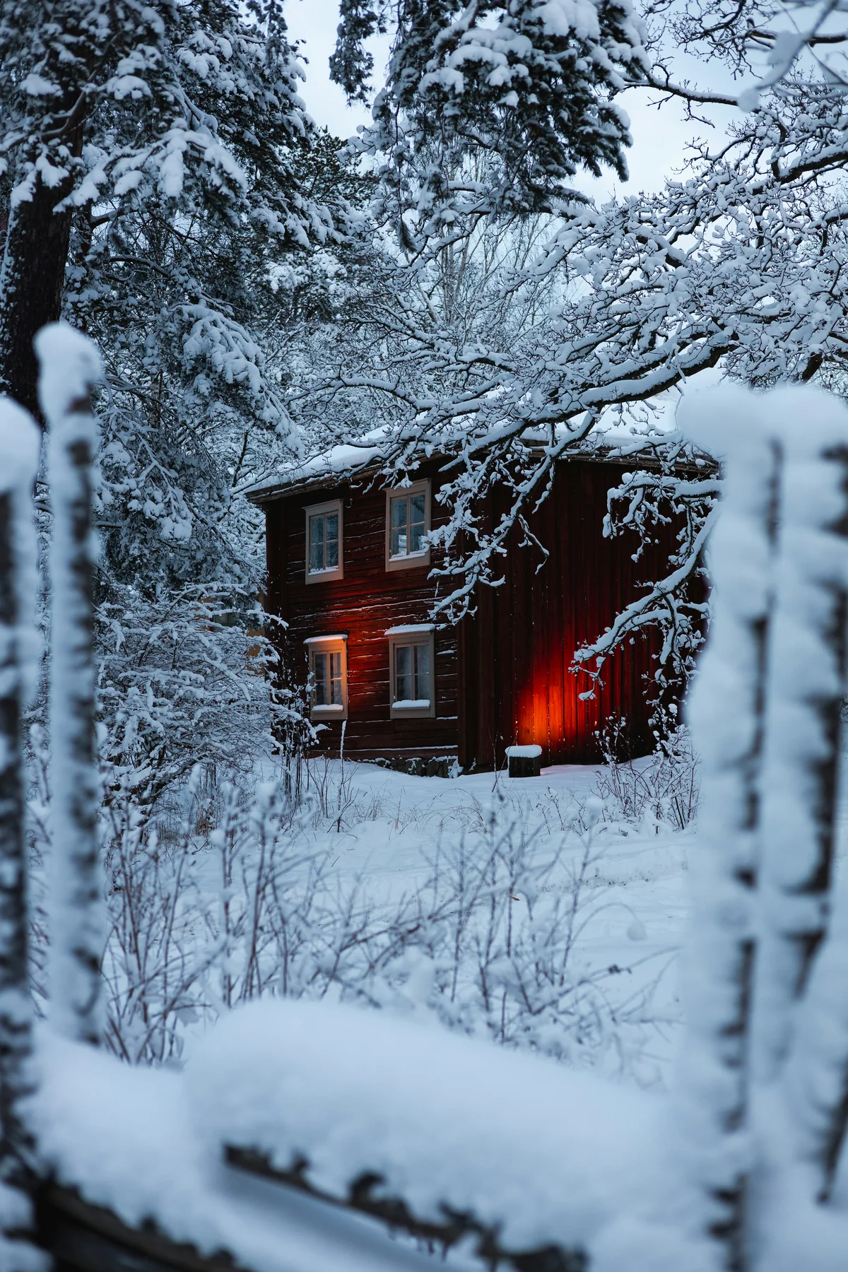 Cabaña de madera con nieve y luz cálida